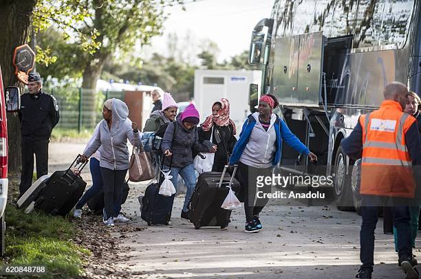 Refugees women, surrounded by the staff of the association "La Vie Active" and police, carry their luggages as they walk to climb into a bus...