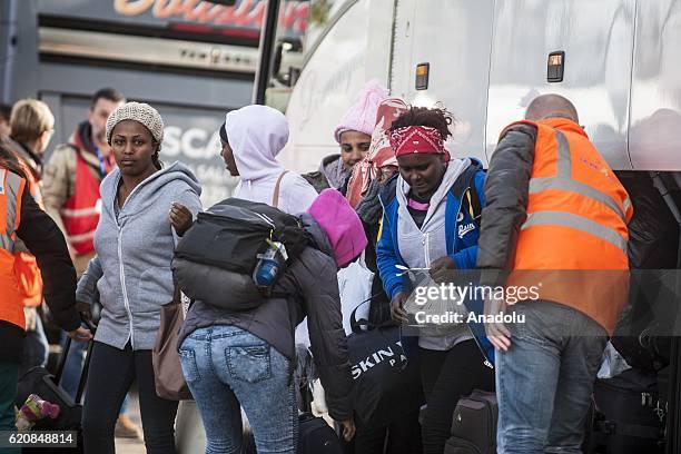 Women refugees, surrounded by the staff of the association "La Vie Active" carry their luggages as they walk to climb into a bus after-leaving the...