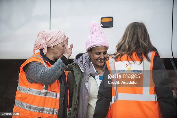 Refugee, surrounded by the staff of the association "La Vie Active" carry her luggages as she walk to climb into a bus after leaving the "Jules...