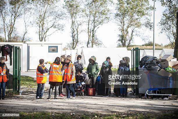 Refugee families are waiting with their luggages to climb into a bus after-leaving the "Jules Ferry" center reception, in Calais, on November 3,...
