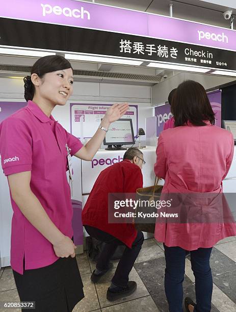 Natori, Japan - A ground worker guides check-in for a flight of Peach Aviation Ltd. At Sendai Airport on April 12, 2013. The Japanese low-cost...