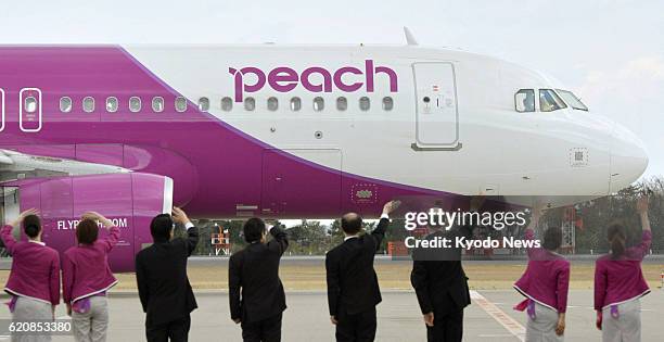 Natori, Japan - Officials and workers wave to the first flight of Peach Aviation Ltd. Leaving Sendai Airport for Kansai International Airport on...