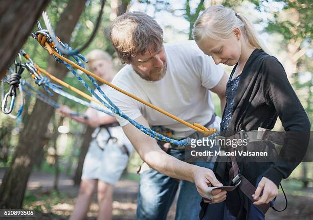 father with 2 children on canopy tour with saftey equipment - season 14 stockfoto's en -beelden