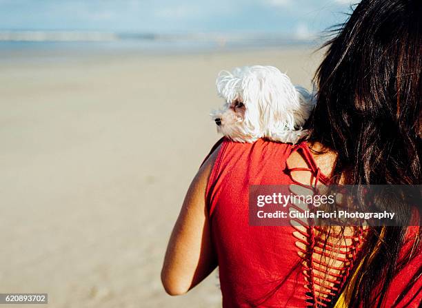 young woman carrying puppy on her shoulder - rimini fotografías e imágenes de stock