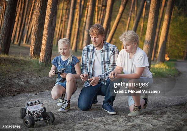 father with his 2 children playing with remote controlled car - remote controlled photos et images de collection