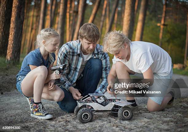 father with his 2 children playing with remote controlled car - remote controlled photos et images de collection