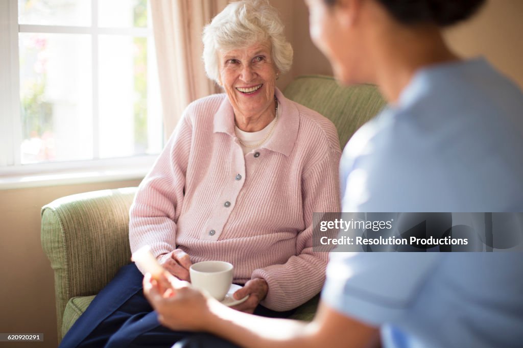 Nurse and patient drinking tea on sofa