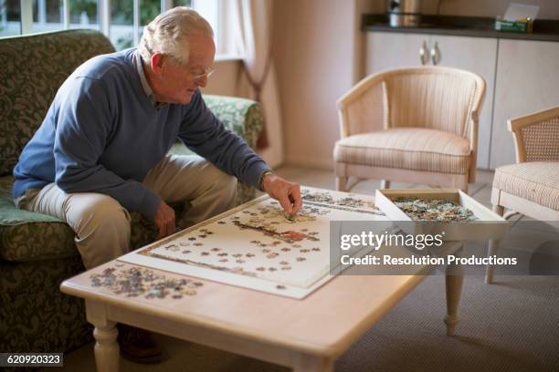 older man on sofa solving jigsaw puzzle - 80s living room fotografías e imágenes de stock