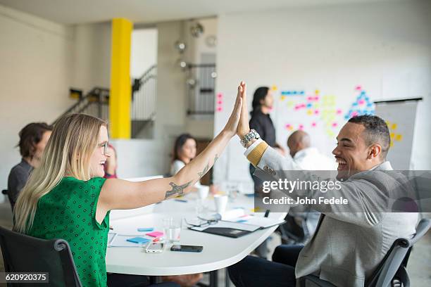 business people high-fiving in office meeting - team office high five foto e immagini stock