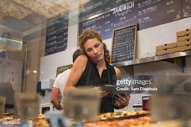 caucasian woman talking on cell phone in cafe - mature women cafe stock pictures, royalty-free photos & images