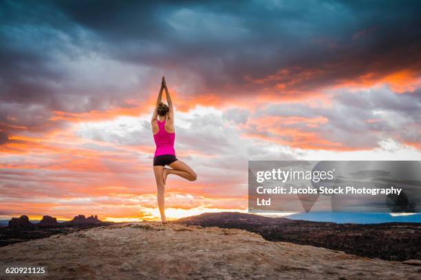 hispanic woman practicing yoga on remote hilltop - moab stock pictures, royalty-free photos & images