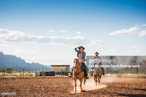 hispanic couple riding horses on ranch - pferdeartige stock-fotos und bilder