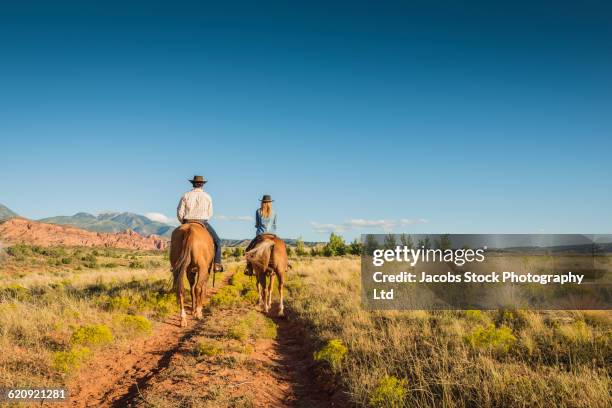 hispanic couple riding horses on rural path - american ranch landscape stock-fotos und bilder