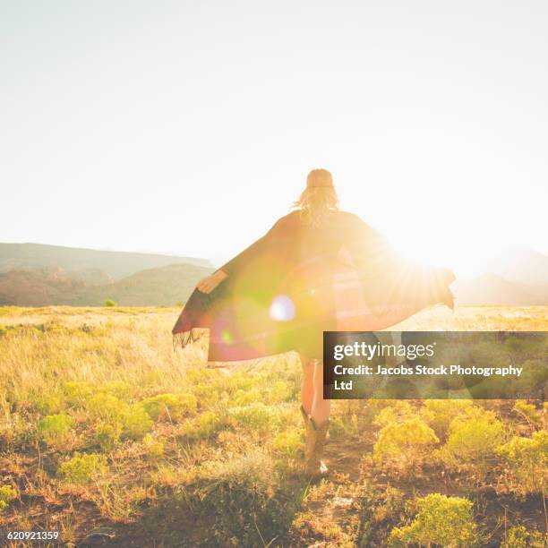 hispanic woman walking in remote field - shawl fotografías e imágenes de stock