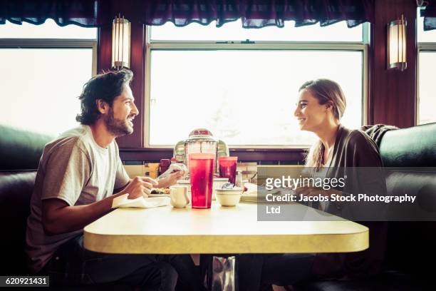 hispanic couple eating breakfast in diner - breakfast restaurant stock pictures, royalty-free photos & images