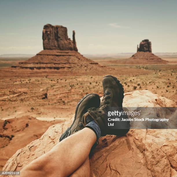 Hispanic hiker resting boots on rock formation