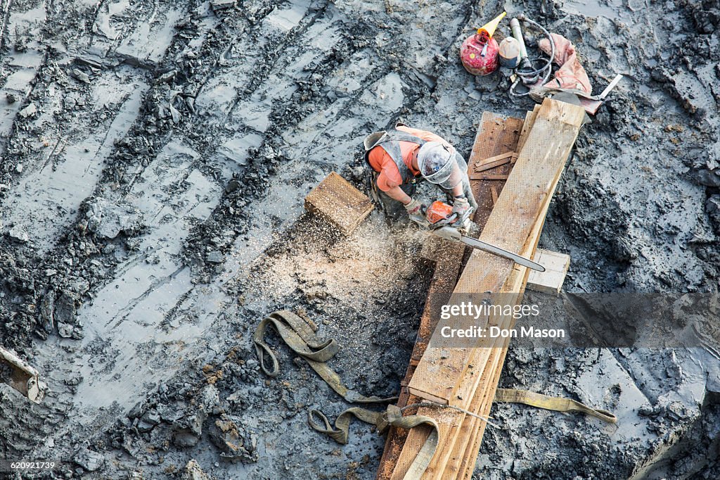 Caucasian worker sawing wood at construction site