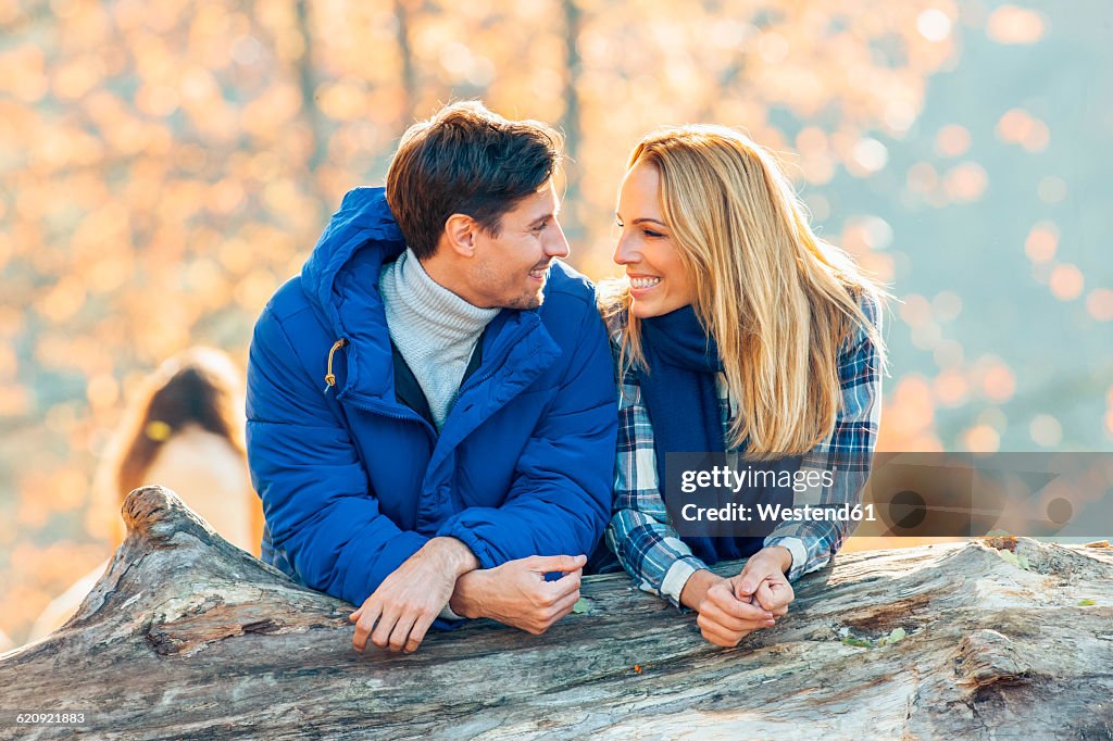 Happy couple behind a trunk smiling at each other