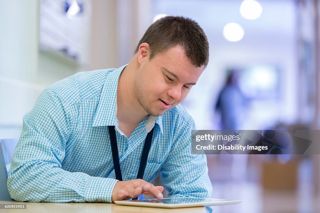 Caucasian man with Down Syndrome using digital tablet in hospital