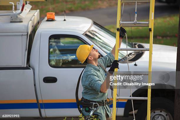 caucasian worker raising ladder outdoors - cable installer stockfoto's en -beelden