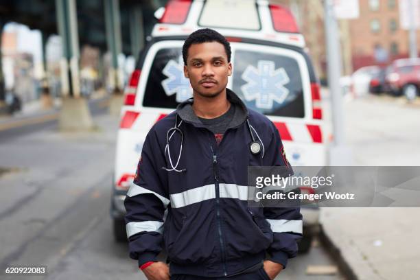 mixed race paramedic standing near ambulance - 911 new york stockfoto's en -beelden