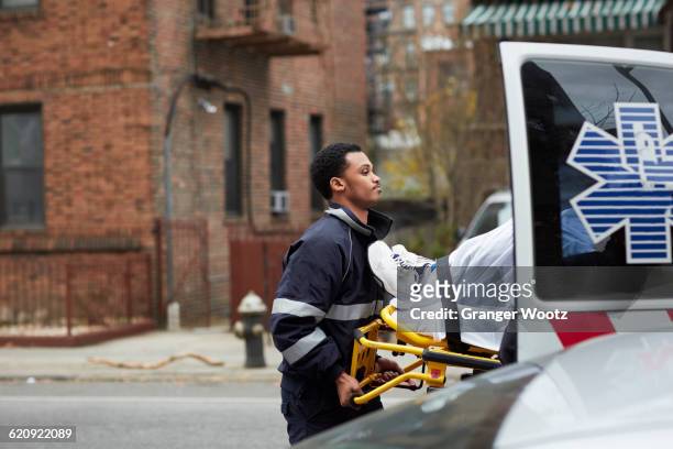 mixed race paramedic loading patient into ambulance - 救急救命士 ストックフォトと画像