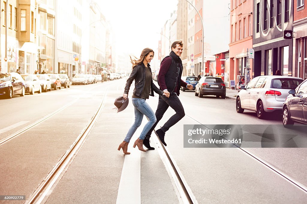 Germany, Berlin, happy couple crossing a street