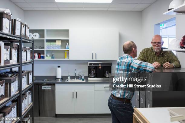 businessmen talking in office kitchen - cafeteria foto e immagini stock