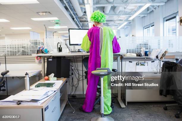 caucasian businessman wearing clown costume in office - clown photos et images de collection