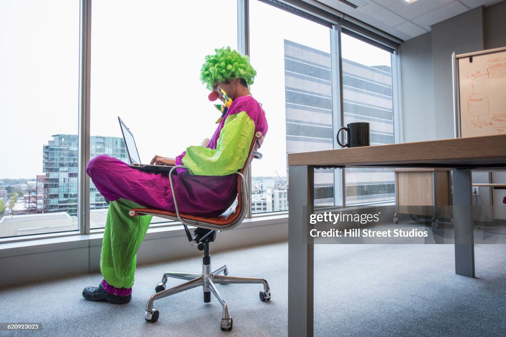 Caucasian businessman wearing clown costume in office