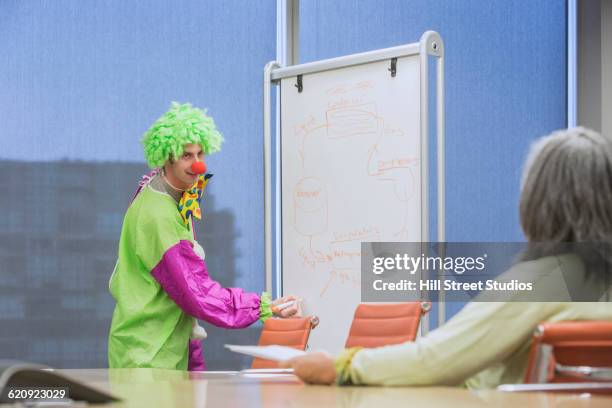 businessman wearing clown costume in office - funny clown stockfoto's en -beelden