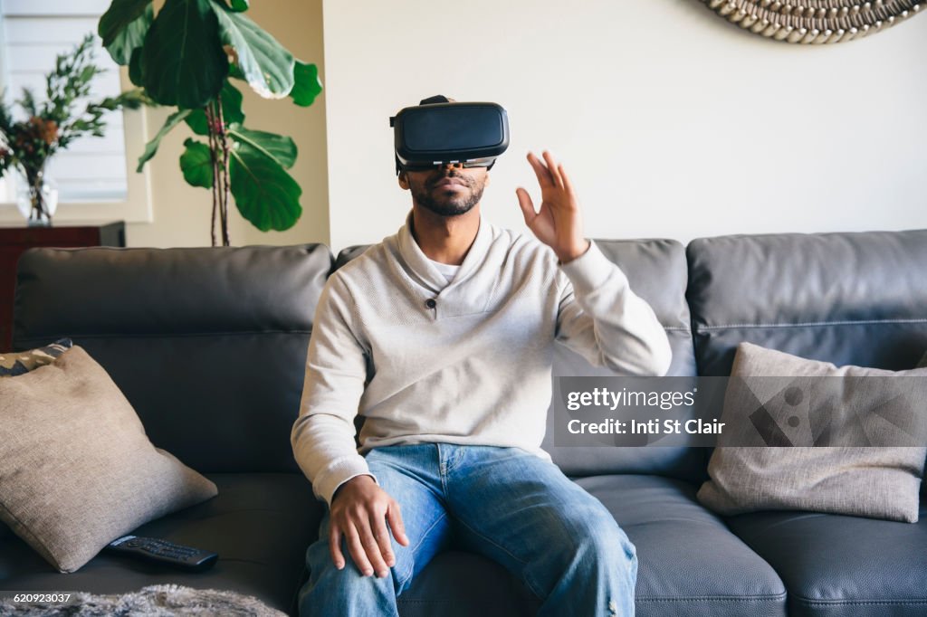 Mixed race man using virtual reality goggles