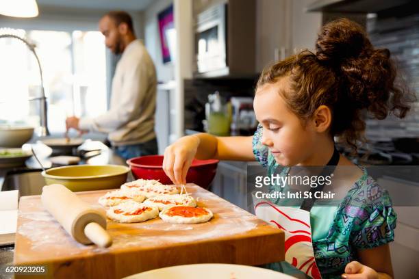 mixed race girl cooking in kitchen - kids cooking stock-fotos und bilder