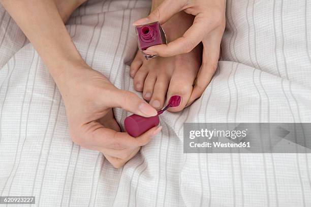 young woman on bed painting her toenails - painting toenails stock-fotos und bilder