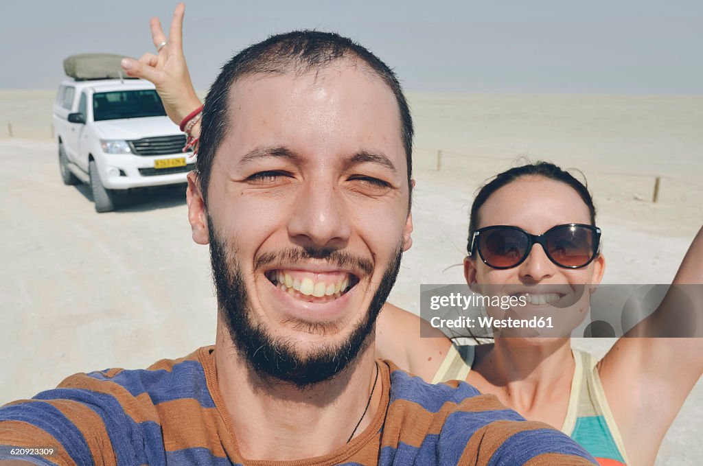 Namibia, Etosha National Park, happy couple with a 4x4 tented car in the large Etosha salt pan