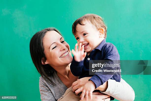 portrait of happy mother with her little son in front of green background - family on coloured background stock pictures, royalty-free photos & images