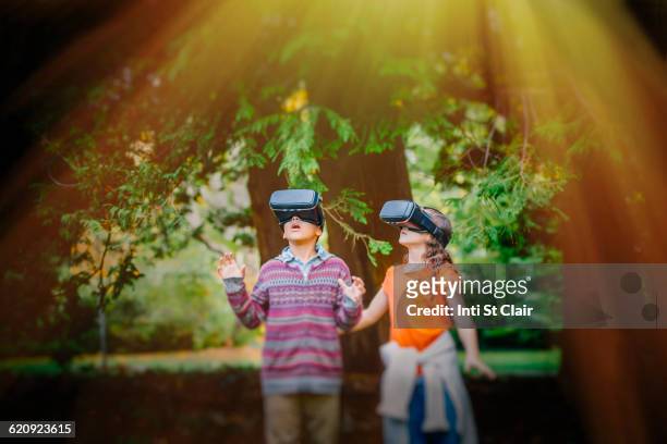 mixed race children using virtual reality goggles outdoors - afrikanisches kind beobachtet natur stock-fotos und bilder