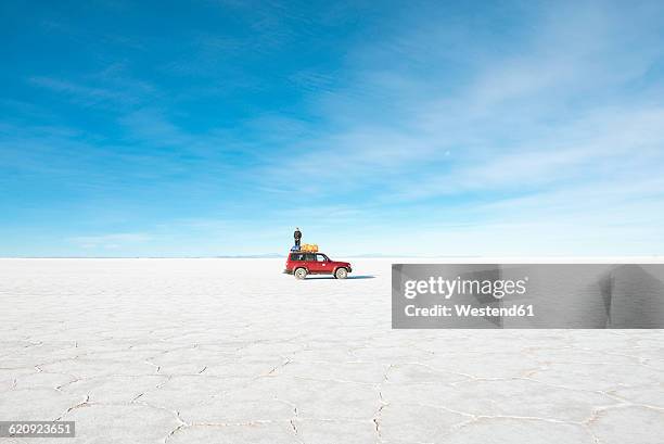 bolivia, atacama, altiplano, salar de uyuni, man standing on a 4x4 car - lago salato foto e immagini stock