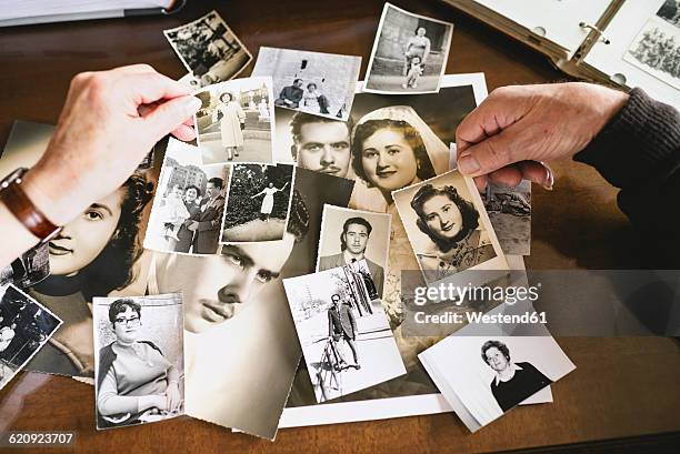 hands of senior couple holding old photographies of themselves - album de fotos fotografías e imágenes de stock