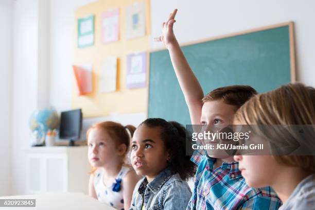 student raising hand in classroom - solo bambini foto e immagini stock