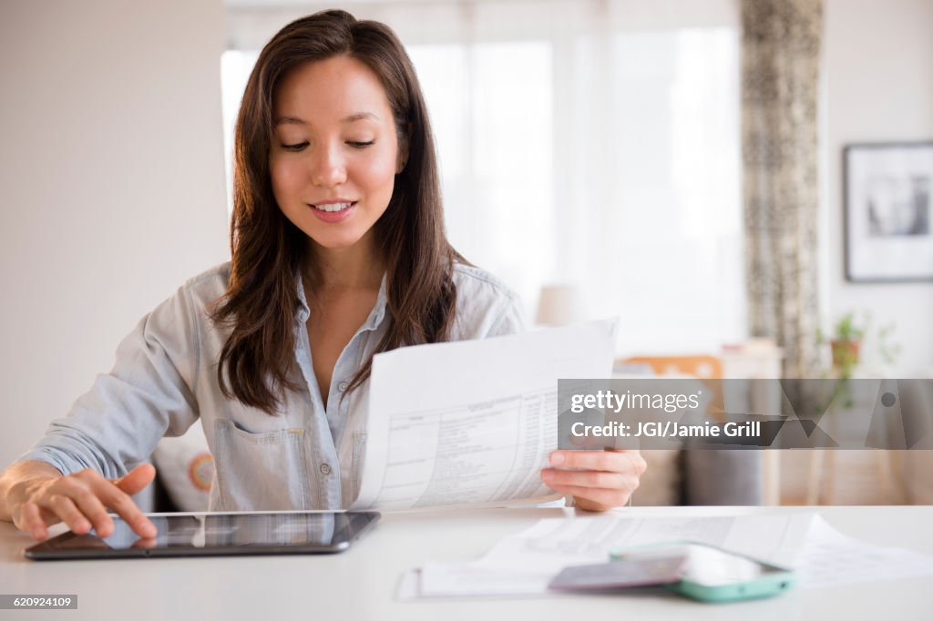 Mixed race woman paying bills on digital tablet