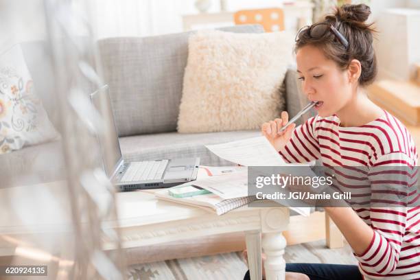 mixed race woman paying bills on laptop - home budget stockfoto's en -beelden