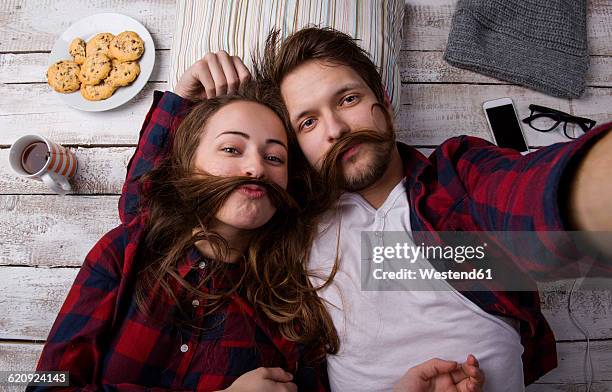 portrait of young couple lying on the floor taking a selfie - hair love stock pictures, royalty-free photos & images