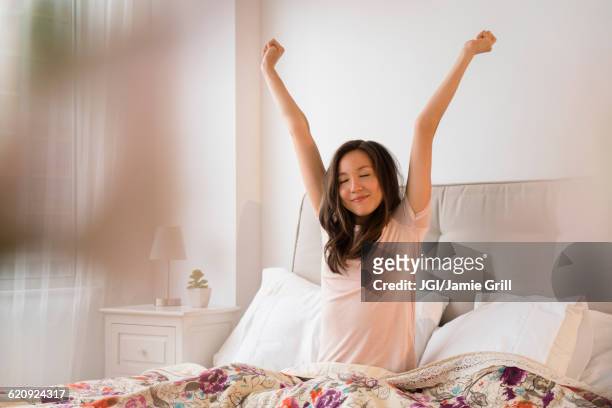 mixed race woman stretching in bed - good morning ストックフォトと画像