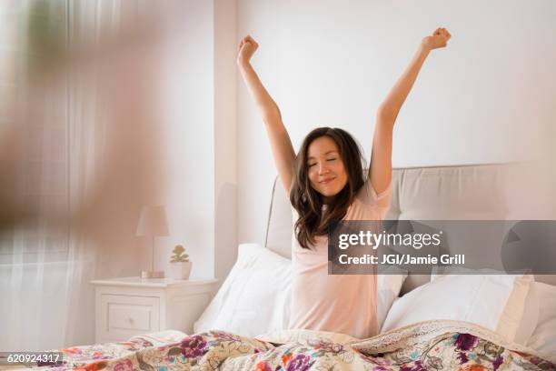 mixed race woman stretching in bed - acordando - fotografias e filmes do acervo