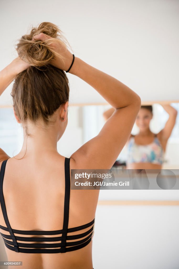 Mixed race dancer tying hair in bun