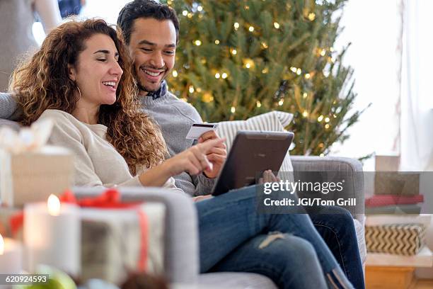 couple shopping with digital tablet on sofa - christmas shopping ストックフォトと画像