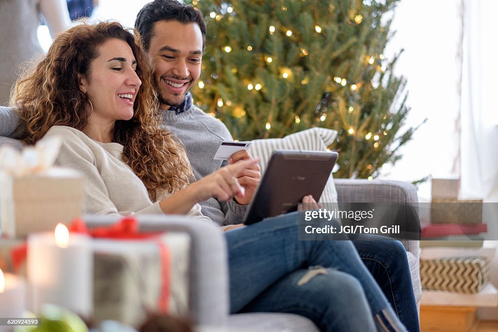 Couple shopping with digital tablet on sofa