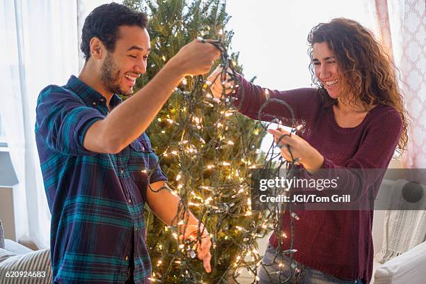 couple decorating christmas tree - untangle stock-fotos und bilder