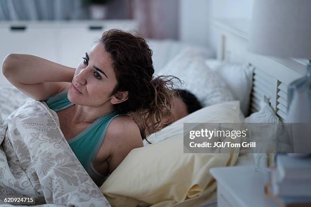woman rubbing her neck in bed - bad relationship foto e immagini stock